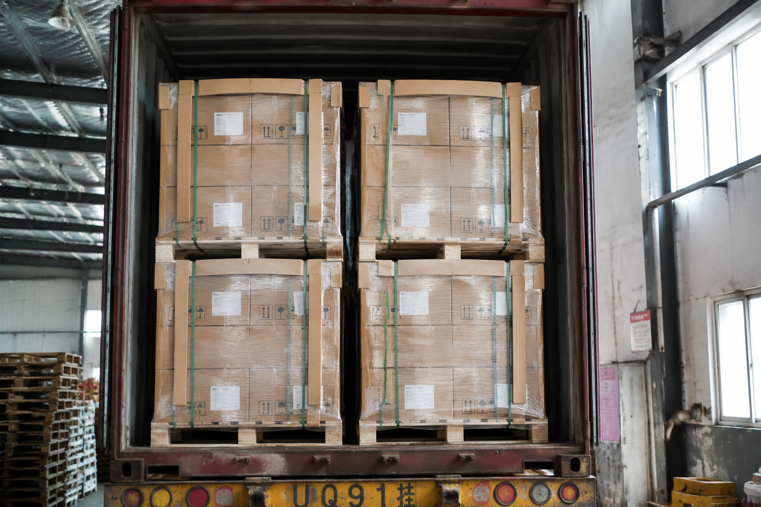 Palletized packaging cartons loaded into a shipping container with stretch wrap and visible shipping marks