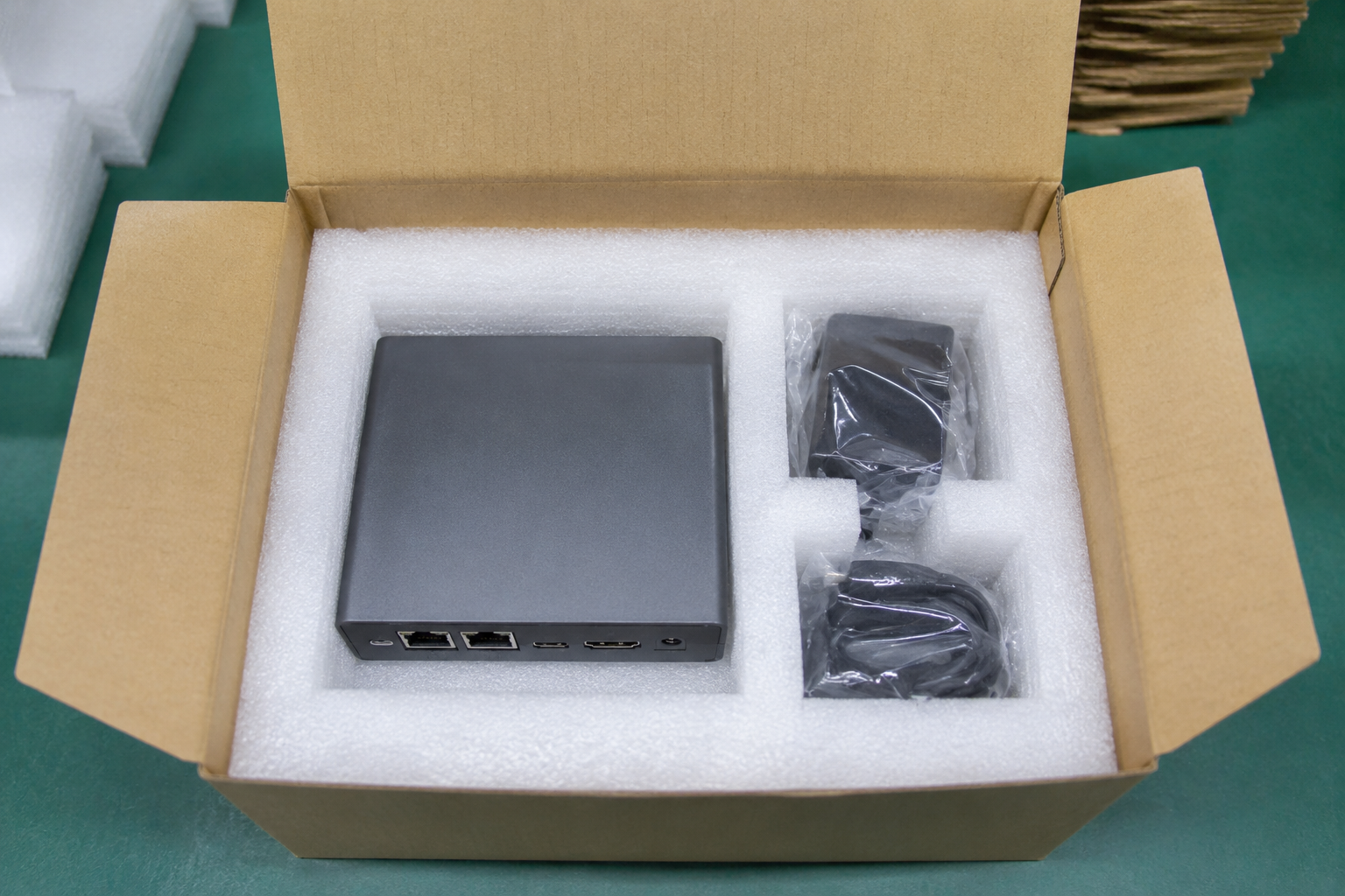 EPE foam insert holding a compact electronics device with bagged charger cable and adapter beside it